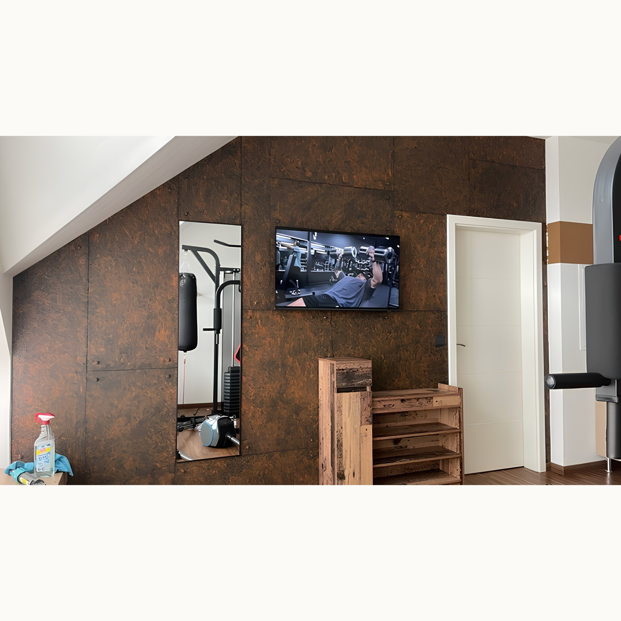 Fitnessraum unter Dachschräge mit rostbrauner Wand, Fernseher, Spiegel und Trainingsgeräten