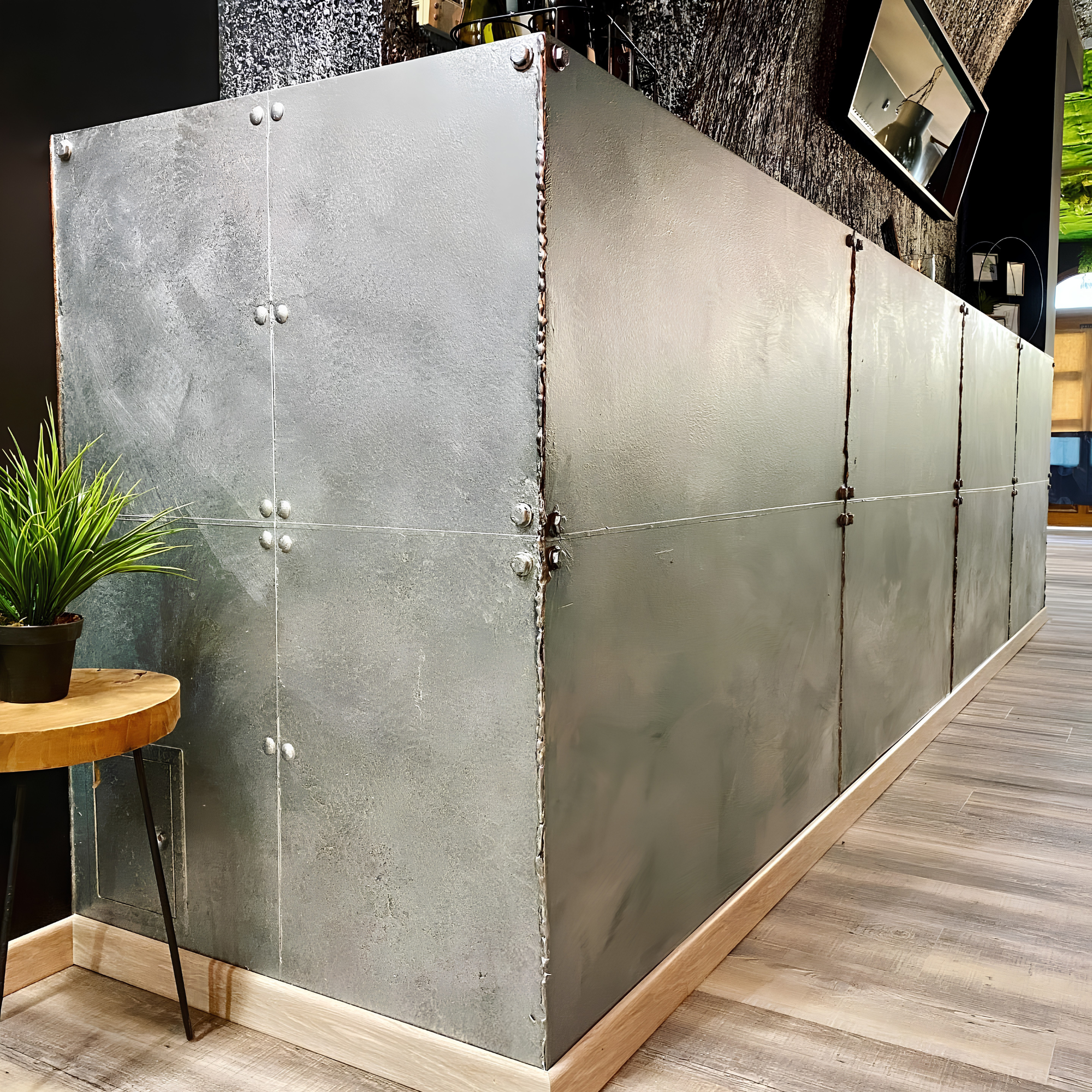 Silberfarbene, genietete Metalltheke im Industrie-Look, seitliche Ansicht mit Zimmerpflanze